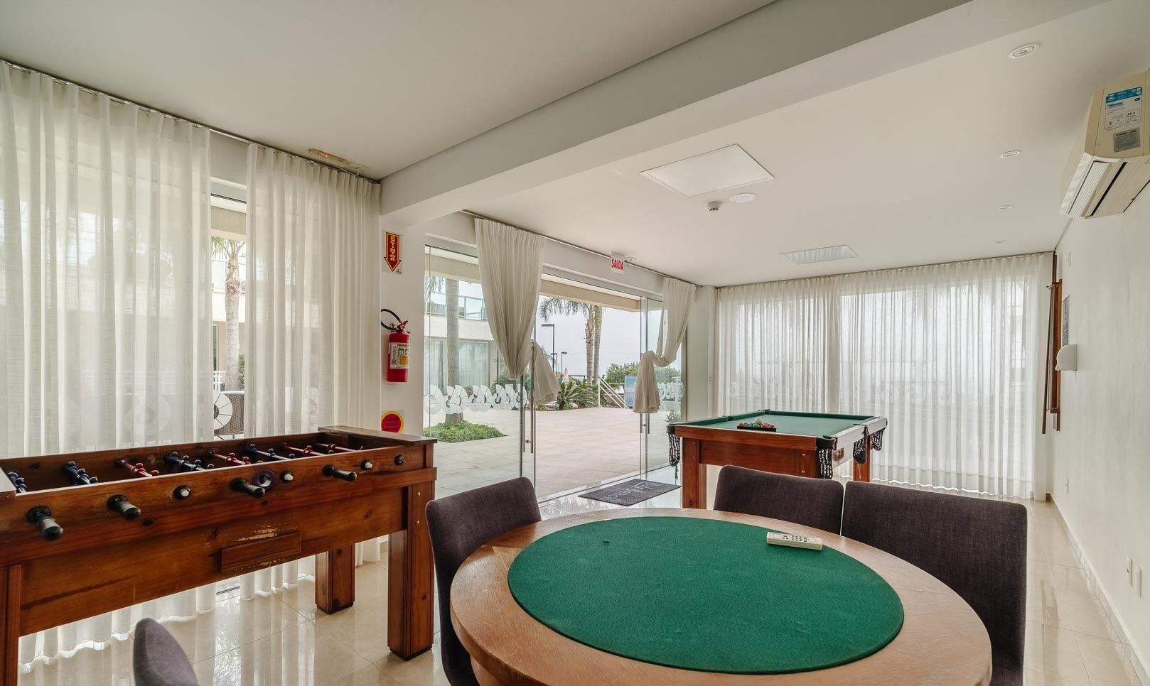 A room with a pool table, foosball table, and a billiards table.