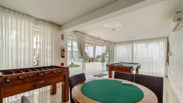 A room with a pool table, foosball table, and a billiards table.