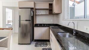 Una cocina moderna con refrigerador de acero inoxidable, gabinetes de madera, encimera de granito y ventana con vistas.