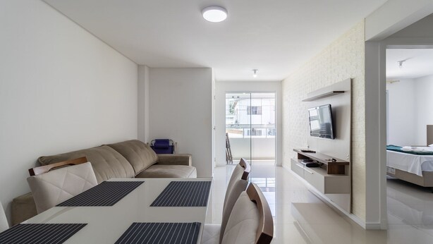 Una sala de estar moderna y bien iluminada, con sofá, mesa de comedor y televisor.