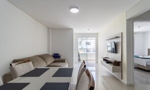 Een moderne, goed verlichte woonkamer met een bank, eettafel en televisie.