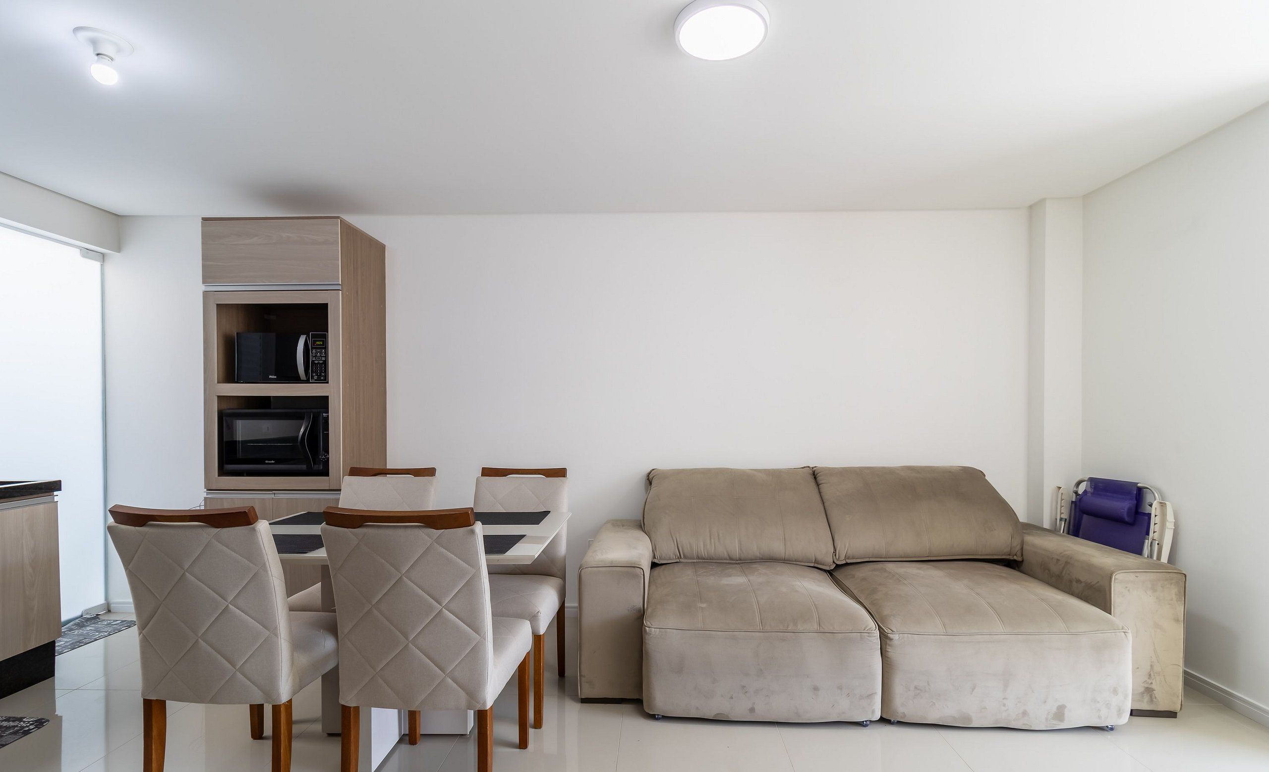 Una sala de estar moderna con un sofá color beige, una mesa de comedor con sillas y armarios empotrados.