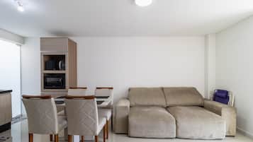 A modern living room with a beige sofa, a dining table with chairs, and built-in cabinetry.