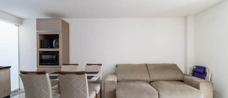 Una sala de estar moderna con un sofá color beige, una mesa de comedor con sillas y armarios empotrados.
