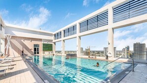 En pool på taget med krystalklart vand, udsigt over byens skyline og moderne arkitektur.