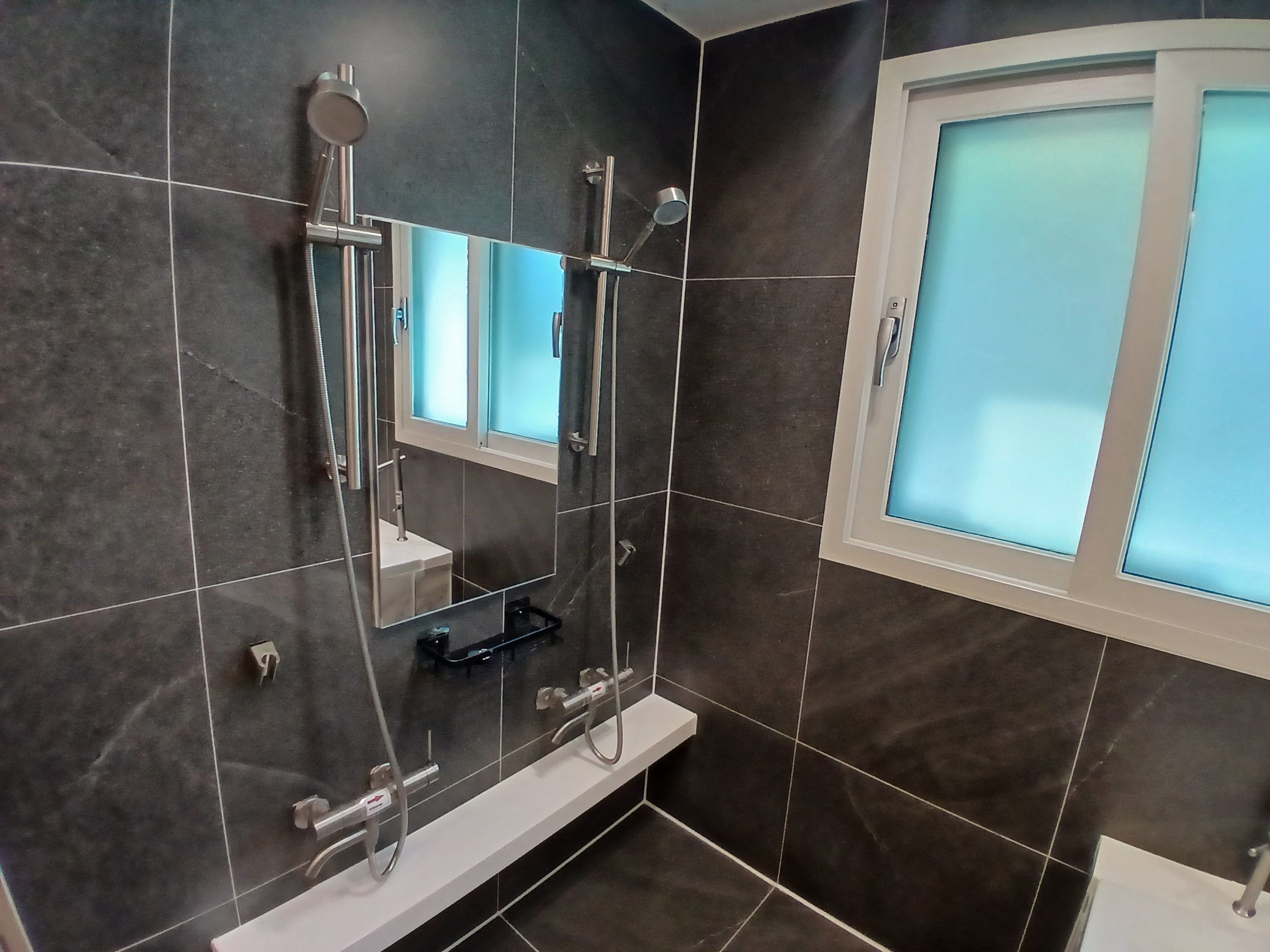 Un baño moderno con cabina de ducha de vidrio, lavamanos integrado y un espejo.