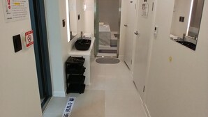 Un pasillo de hotel con un lavabo, un espejo y una puerta que da a un baño.