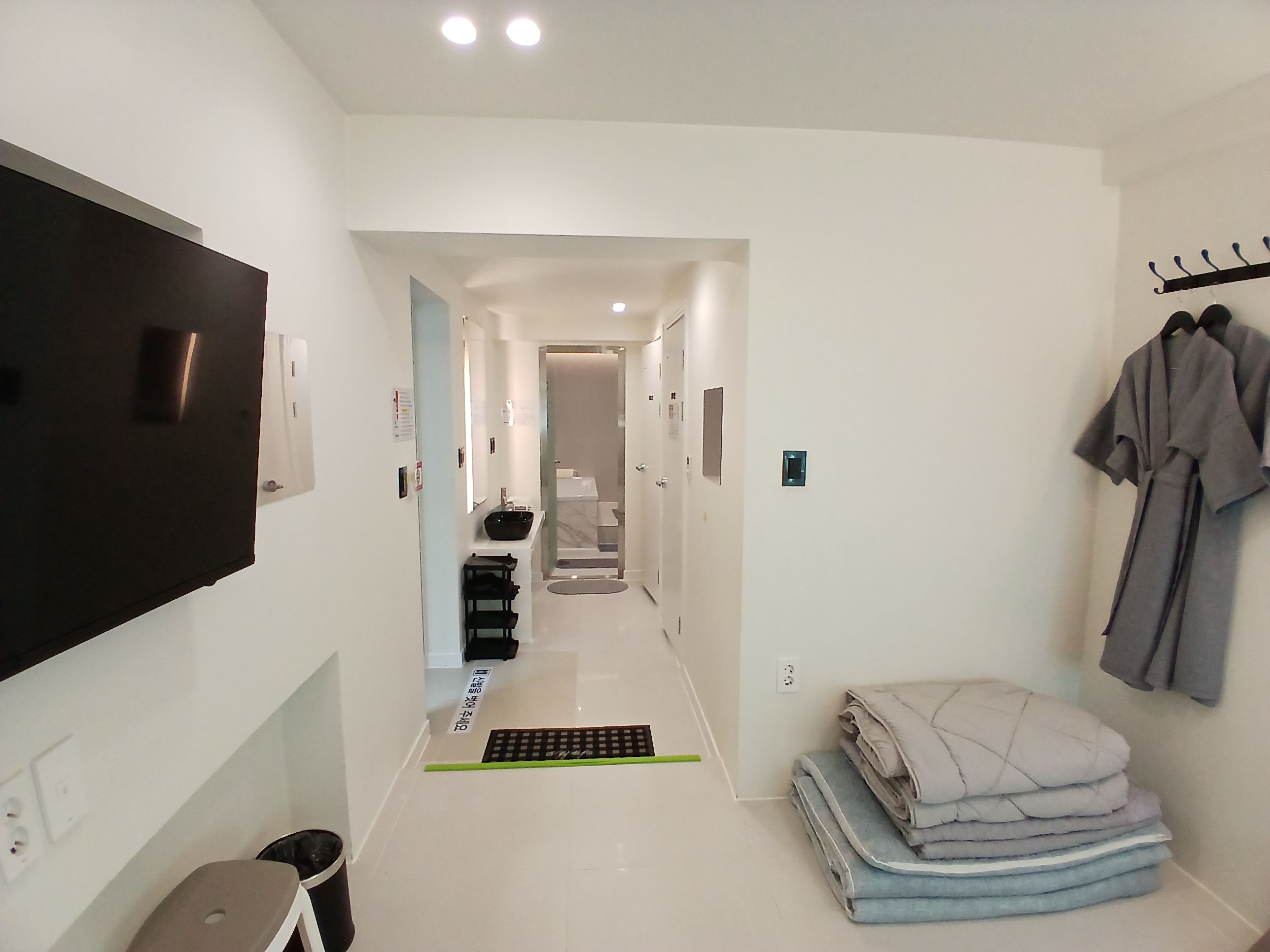 Un couloir d’hôtel avec un téléviseur, un porte-manteau et une pile de serviettes.