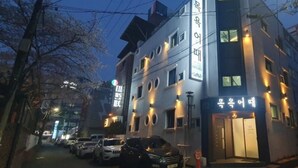 Un edificio de varios pisos con spa y restaurante en la planta baja, que presenta un diseño moderno con ventanas iluminadas y una entrada visible.