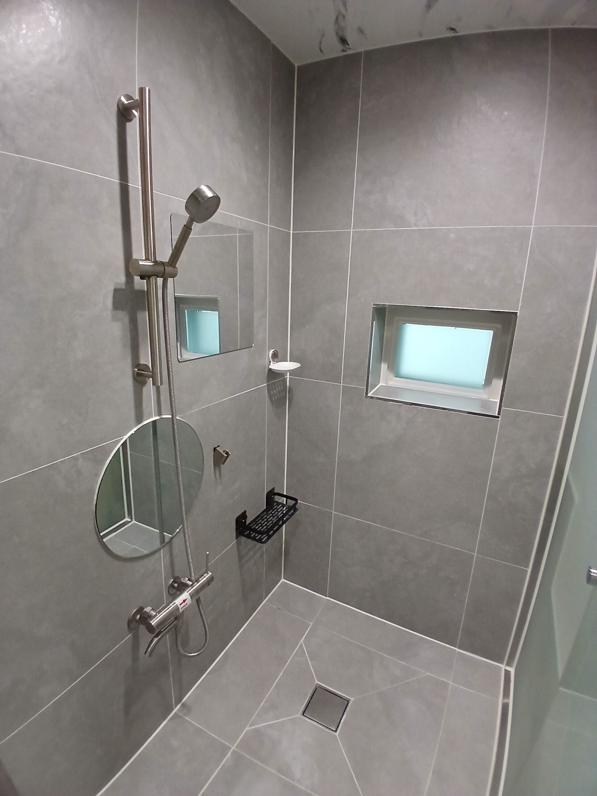 A modern bathroom with a shower, a sink, and a mirror.