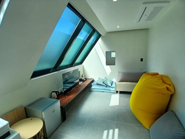 A modern, compact room with a skylight, a bed, a desk, and a small seating area. - MOGYOG EOTTAE SPA MOTEL (Pohang)