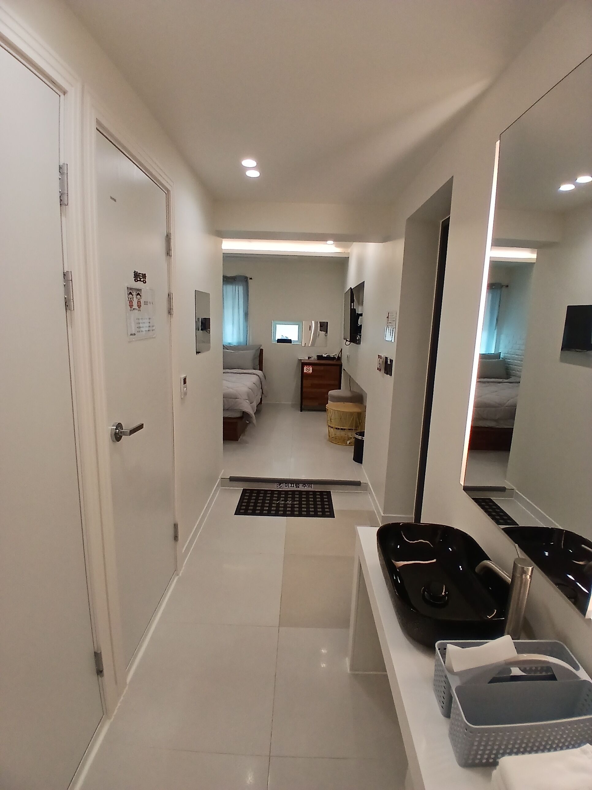 A hotel room with a bed, a desk, a mirror, and a bathroom.