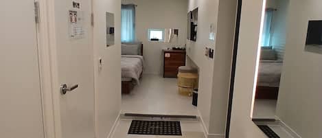A hotel room with a bed, a desk, a mirror, and a bathroom.