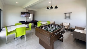A modern indoor space with a foosball table, bright green chairs, and a pool table. - Makeva Condos - Near Malecon (Mazatlán)