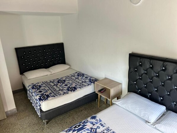 A hotel room with a large bed, a smaller bed, a nightstand, and a headboard with a diamond pattern. - Hotel Urbano 70 (Medellín)