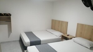 Hotelkamer met twee bedden, een houten hoofdbord, een nachtkastje en een plank met een decoratief object.