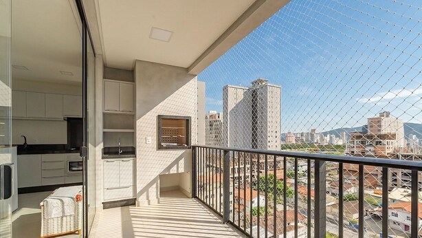 Un balcón con vistas a un paisaje urbano, incluyendo edificios altos y un cielo despejado.