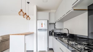 Una cocina moderna con refrigerador empotrado, estufa a gas e iluminación colgante.