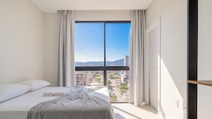 Un dormitorio con un ventanal grande, una cama y vistas a la ciudad.