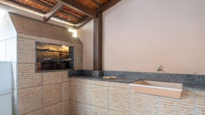 A kitchen with a brick backsplash, a countertop, and a built-in oven. - Casa a 4 min a pé da praia em Porto Belo BRR0097 (Porto Belo)