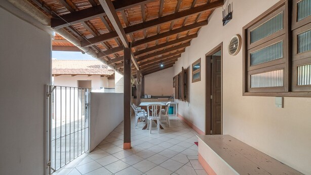 A corridor with a tiled floor, a wooden ceiling, and a table with chairs. - Casa a 4 min a pé da praia em Porto Belo BRR0097 (Porto Belo)