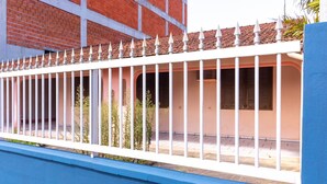 A building with a white fence topped with pointed elements, a pink wall, and a blue baseboard. - Casa a 4 min a pé da praia em Porto Belo BRR0097 (Porto Belo)