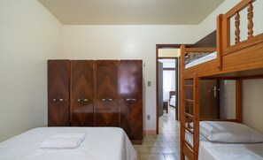 A bedroom with a bunk bed, a wardrobe, and a bed with a neatly folded towel. - Casa a 4 min a pé da praia em Porto Belo BRR0097 (Porto Belo)