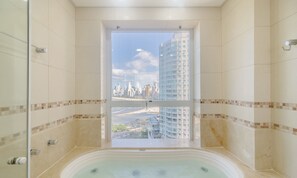 Een badkamer met een bad, een douche en uitzicht op een stadsbeeld door een groot raam.