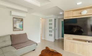 A modern living room with a sofa, a flat-screen TV, and a wooden cabinet. - 3BR Apt sea View & Ferris Wheel BC Bsd1501 (Balneário Camboriú)