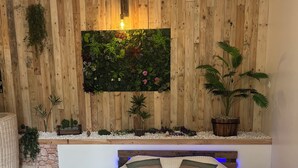 Une chambre avec un lit, un mur en bois, une plante fixée au mur et une petite table.