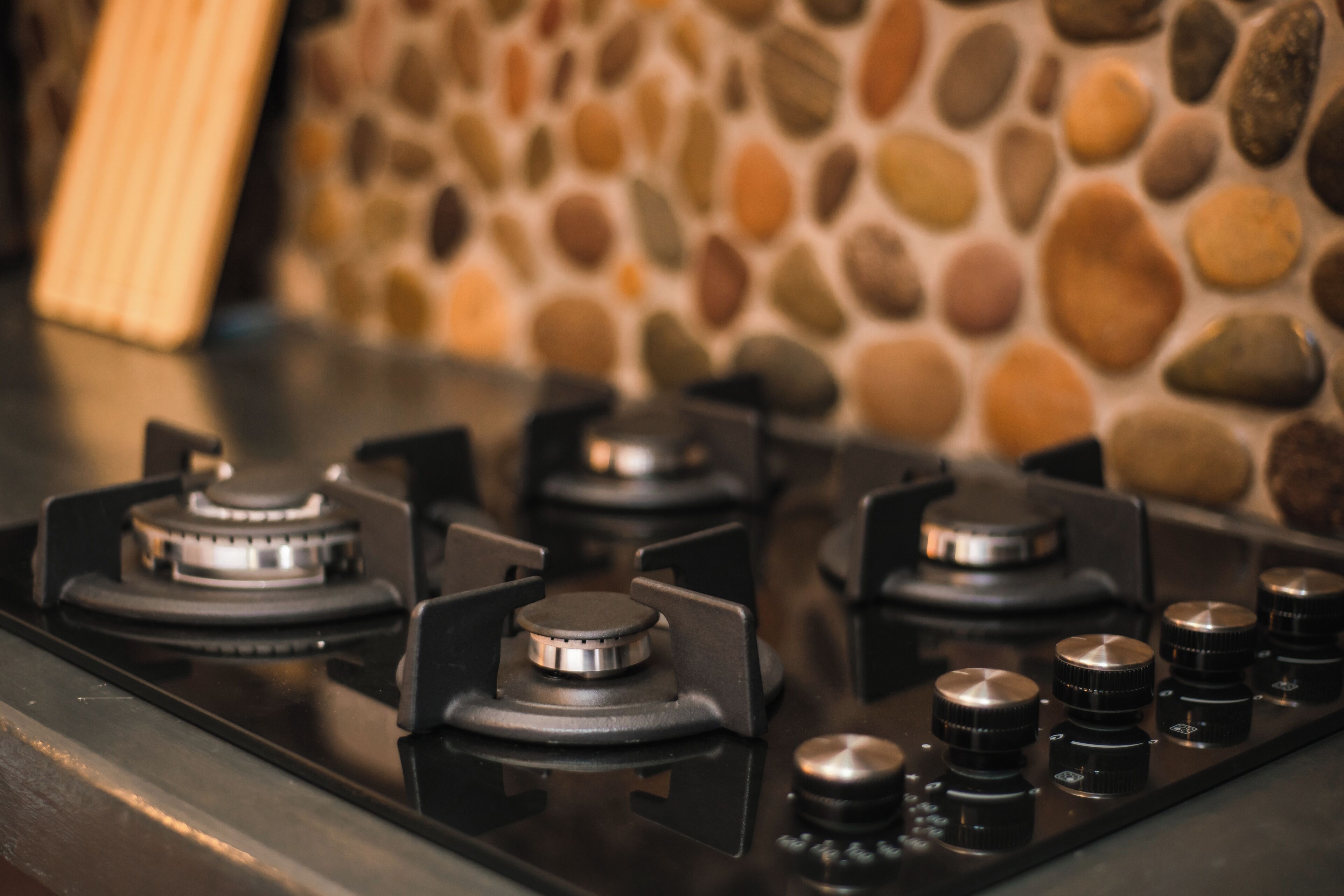 A kitchen with a gas stove and a stone wall in the background.