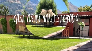 A courtyard with a pergola, a table, and chairs, surrounded by a brick wall and a mountain view. - Family friendly 5-bedroom home in the Sacred Valley (Calca)