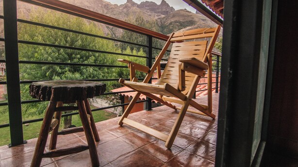 A wooden chair and stool on a balcony with a view of green mountains. - Family friendly 5-bedroom home in the Sacred Valley (Calca)