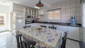 A modern kitchen with a dining table, cabinets, and a water dispenser. - 5BR Home w/ Pool in Penha Center Bsl190 (Penha)