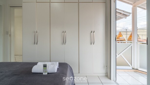 A bedroom with a bed, a digital thermostat, and a view of the outside through a sliding glass door. - 5BR Home w/ Pool in Penha Center Bsl190 (Penha)