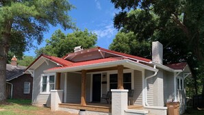 A single-story house with a red roof, a front porch with steps, and a chimney. - Three Bedroom Downtown Cottage (Lincolnton)
