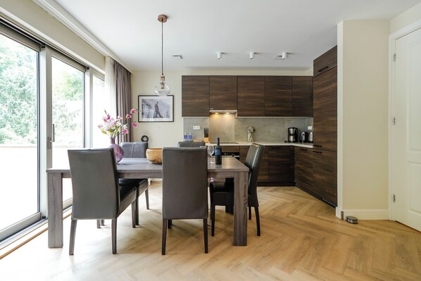 Uma cozinha moderna com armários de madeira escura, uma mesa de jantar com cadeiras e uma janela grande que proporciona luz natural.
