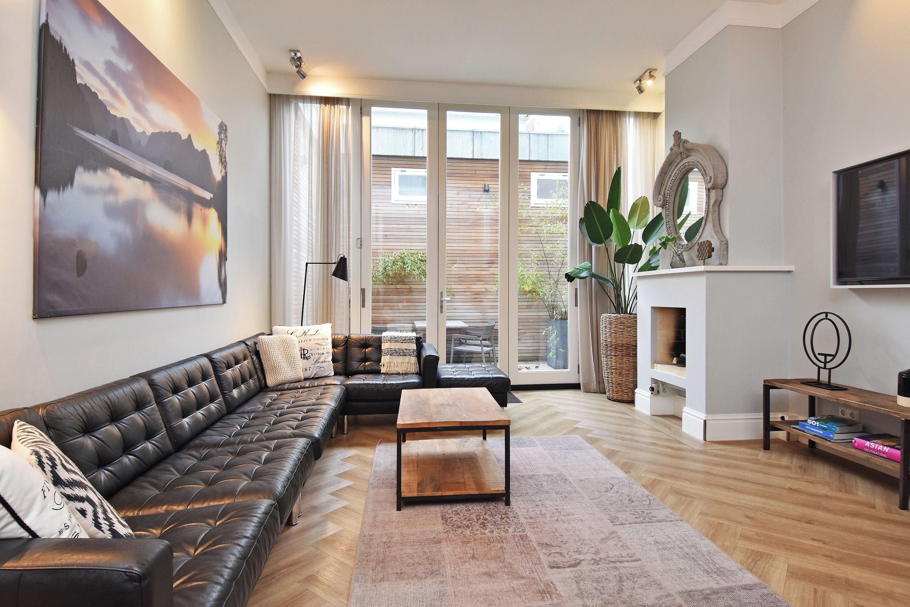 A living room with a leather sofa, a wooden coffee table, and a large painting on the wall.