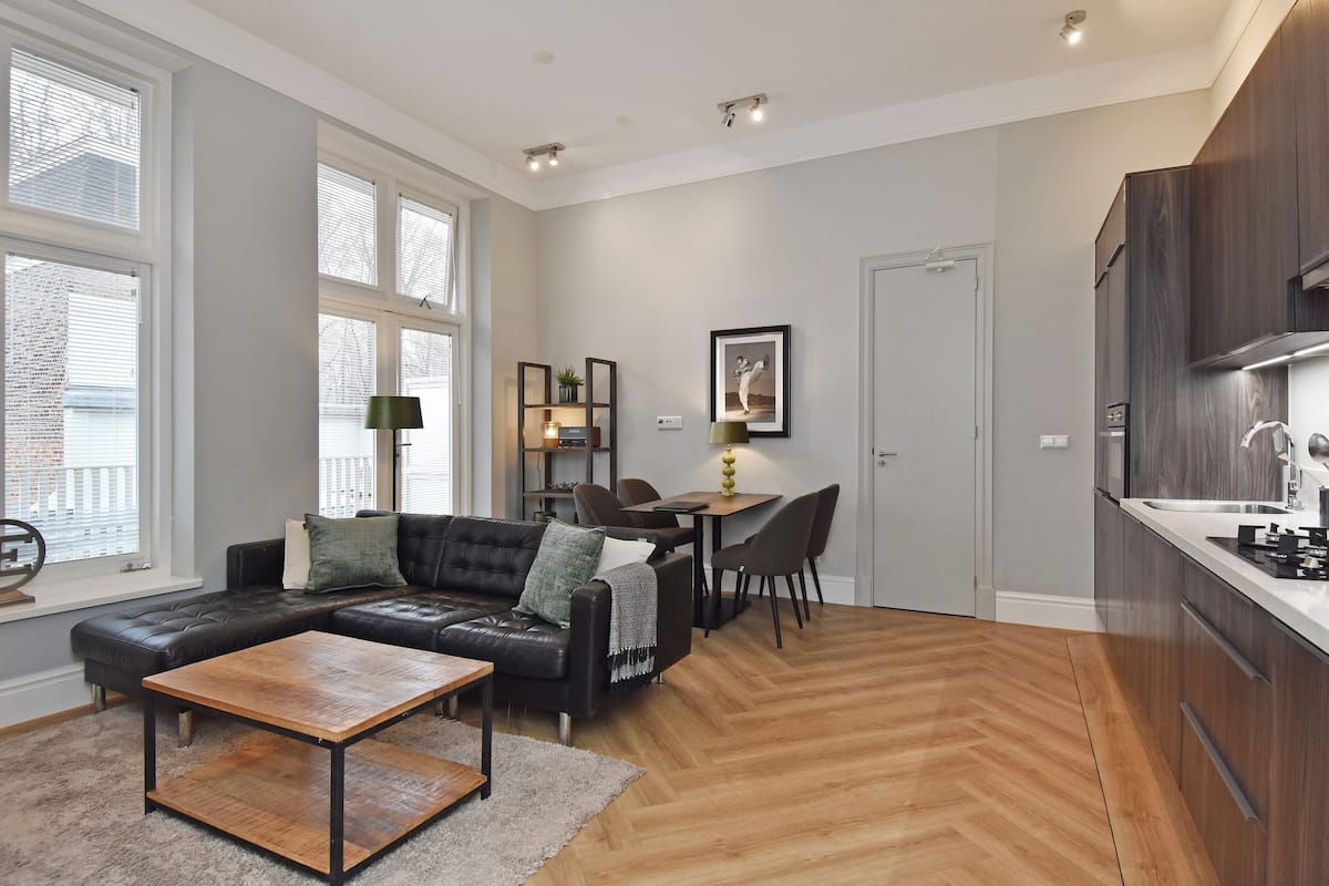 A modern living room with a leather sofa, a wooden coffee table, and a dining area with a table and chairs.