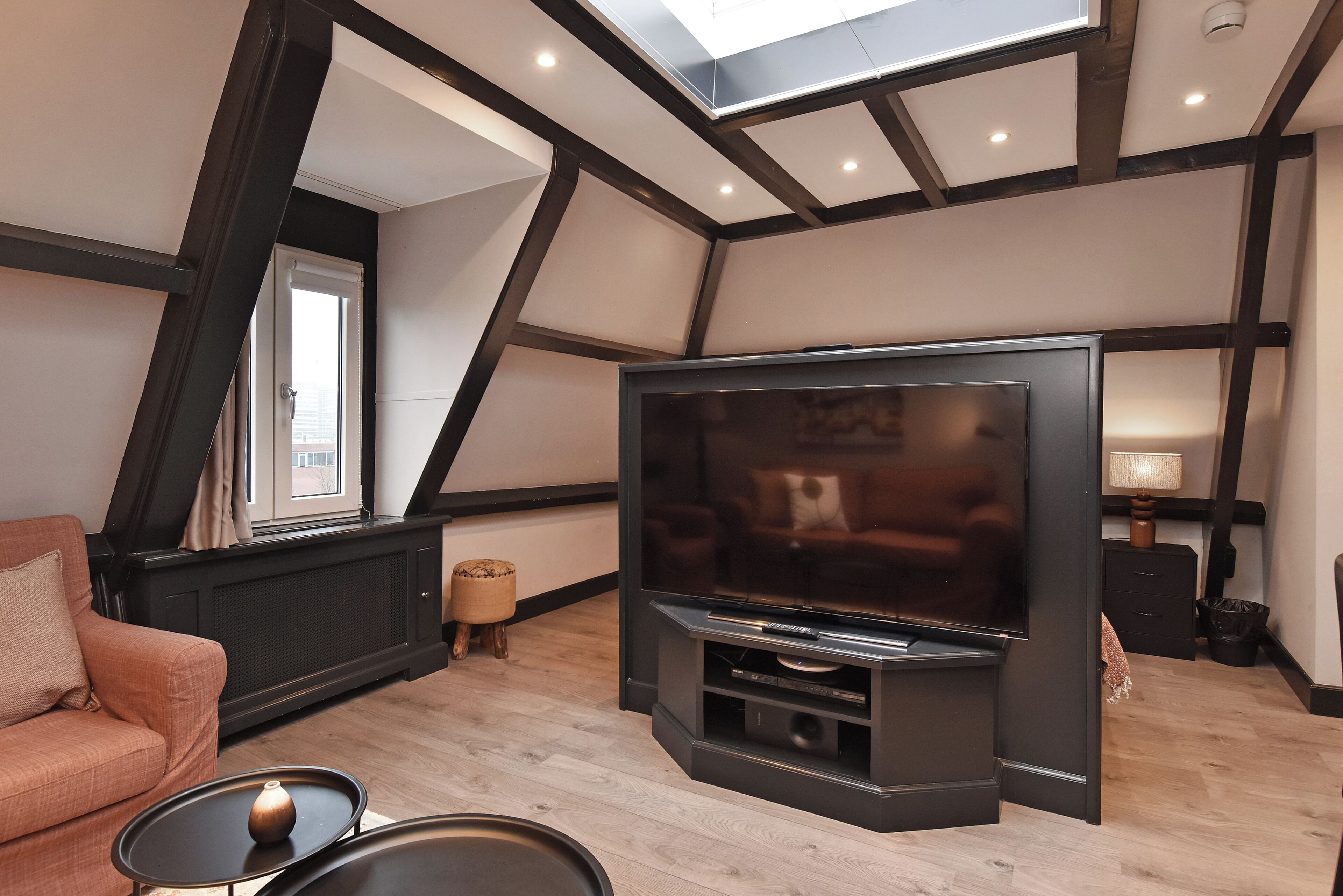 A modern living room with a large flat-screen TV, a sofa, and a small side table.