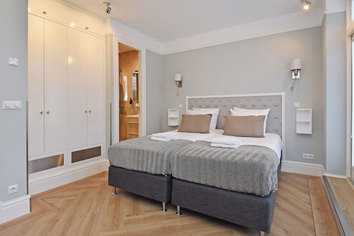 A bedroom with a large bed, a wardrobe, and a bathroom visible through an open door.