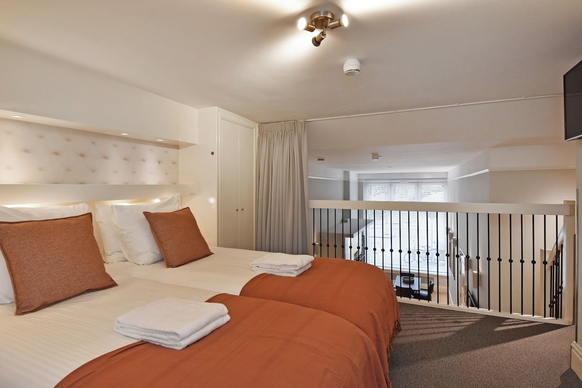 A hotel room with two beds, a balcony, and a view of the city.
