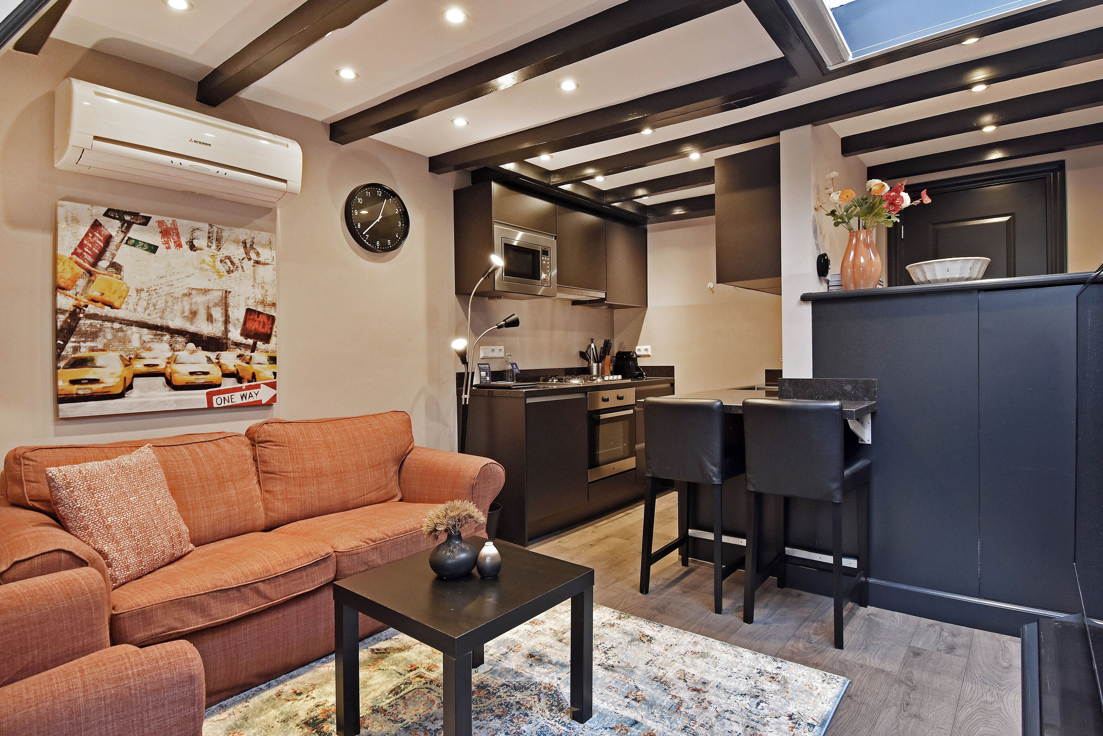 A modern kitchen with a microwave, oven, and sink, a dining area with a table and chairs, and a living room with a sofa and coffee table.