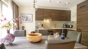 A modern kitchen with wooden cabinets, a dining table with chairs, and a vase with flowers.
