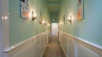 A hallway with a cream-colored wainscoting, light green walls, and several framed posters.