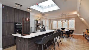 Une cuisine moderne dotée d’un îlot central, de meubles de couleur bois foncé et d’une verrière.