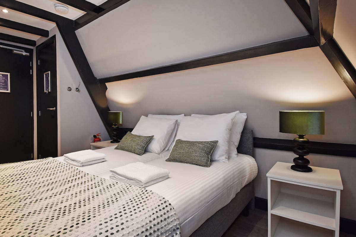 A bedroom with a large bed, two bedside tables, a nightstand, and a ceiling fan.