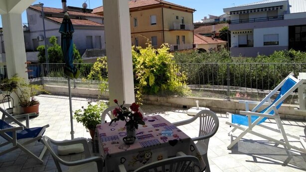 Un espace extérieur abrité, aménagé avec une table, des chaises et des plantes en pot.