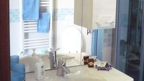 Une salle de bain avec un lavabo blanc, un miroir et une cabine de douche en verre.