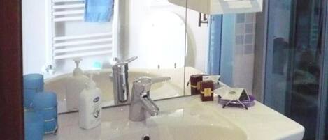 A bathroom with a white sink, a mirror, and a glass shower enclosure.